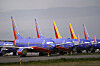 Flere blå Southwest Airlines Boeing 737-fly parkert på bakken ved et industrielt flyanlegg.