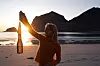 Person på strand i solnedgang holder en heklet nettingveske opp mot lyset.