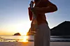 Person på strand ved solnedgang som holder en heklet nettingveske.