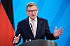 Johann Wadephul taler ved en talerstol foran blå bakgrunn og tysk flagg.