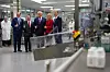 Donald Trump står med en gruppe ledere i et moderne laboratorie- og produksjonsanlegg.