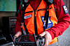 Frivillig i Røde Kors med oransje vest styrer en dronekontroller.
