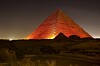 Kheopspyramiden i Giza opplyst i oransje lys om natten.