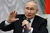 Vladimir Putin sitter i stol i Kreml og taler med mikrofon løftet i hånden.