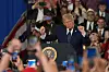 Donald Trump danser bak talerstol med presidentsegl foran en stor folkemengde med mobiltelefoner.
