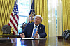 Donald Trump sitter ved skrivebordet i Det ovale kontor og snakker mens han signerer dokumenter.