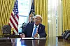 Donald Trump sitter ved skrivebordet i Det ovale kontor og snakker mens han signerer dokumenter.