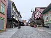 Brosteinsgate omgitt av fargerike trehus og uteservering uten mennesker.