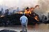 Mann står ved vann og ser mot store flammer og røyk på en åskam på Morland i Sotra