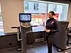 Instruktør ved digitalt treningsapparat i lyst treningsstudio med vinduer mot gaten.