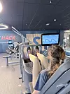 Person trener beinpress på digital treningsmaskin med skjerm i SATS-senter.