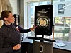 Instruktør peker på stor treningsskjerm i SATS-senter ved vindu.