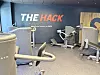 Moderne treningsrom hos SATS med flere digitale styrkeapparater og veggtekst The Hack.