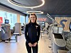Instruktør står i et SATS-treningssenter omgitt av moderne styrkeapparater.