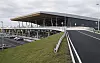 Ytre fasade av ny terminal ved Bergen lufthavn Flesland med rampe og parkering.