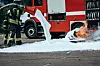 Brannmannskap bruker hvitt skum for å slukke flammer på en asfaltvei foran en brannbil.