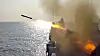 Russisk krigsskip i sjøen avfyrer missil med flamme og røyk langs skipssiden.