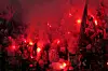 PSG-supportere med røde bluss og flagg på tribunen under kamp i Budapest.