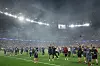 PSG-lag og støtteapparat feirer på banen i en røykfylt Puskas Arena etter finalekamp.