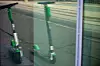 Grønn Lime-elsparkesykkel speilet i en glassflate ved en bygate.