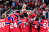 Norske ishockeyspillere i røde drakter løfter bronsetroféet foran publikum.