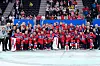 Norges ishockeylag i røde drakter poserer jublende med bronsemedaljer på isen foran supportere.