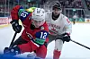Norsk og canadisk ishockeyspiller i tett duell om pucken langs vantet.