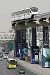 Monorail train on elevated track above a busy Cairo roadway with cars and buses below.