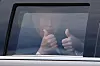 Donald Trump sitter i en mørk presidentlimousine og gir tommel opp gjennom vinduet.