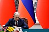Vladimir Putin sitter ved et bord foran russiske og kinesiske flagg under en pressebrief i Beijing.