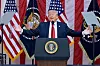Donald Trump står ved en talerstol foran amerikanske flagg under en seremoni.