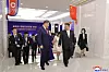 Gruppe av delegater går i en konferansehall med nordkoreanske flagg og bannere på veggene.