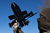 En person i hette demonstrerer en svart anti-droneenhet mot blå himmel.