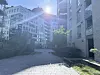 Moderne boligblokker rundt en steinlagt gårdsplass i sterkt sollys.