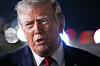 President Donald Trump speaks to reporters in front of blurred airport lights before boarding Air Force One.