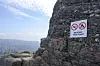 Skilt med forbud mot droneflyging og camping på fjellveggen ved Preikestolen.