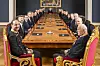 Et langt møtebord i et storslått rom, med kongen, kronprinsen og regjeringen sittende på hver side.