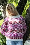 Person står ved et tre og har på seg en rosa, hvit og rød strikkegenser med mønster.