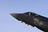 Nærbilde av et mørkt F-35-jagerfly mot blå himmel under avgang.