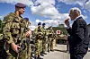 Statsministeren snakker med en norsk soldat i uniform foran flere soldater og militært utstyr på en base.