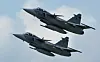 To grå JAS 39 Gripen-jagerfly flyr tett sammen mot en lys himmel.