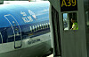 Et KLM-passasjerfly står parkert ved en gate, med en ansatt synlig i et lite vindu i broen.