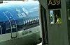 Et KLM-passasjerfly står parkert ved en gate, med en ansatt synlig i et lite vindu i broen.