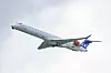 Et SAS-passasjerfly ses fra undersiden mot lys himmel under avgang.