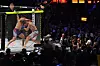 To MMA-utøvere brytes i et bur mens publikum ser på i en mørklagt arena.