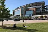 Fans relaxing on the grass near Gillette Stadium with parked vehicles and tailgating in the background.