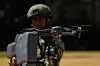 Meksikansk soldat i uniform holder en drone foran kamera under en demonstrasjon utendørs.