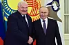 Vladimir Putin og Alexander Lukasjenko står side om side og poserer foran fargerike flagg.