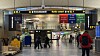 Flyterminal med reisende, sikkerhetskontroll, innsjekkingsområder og opplyste avgangsskilt.