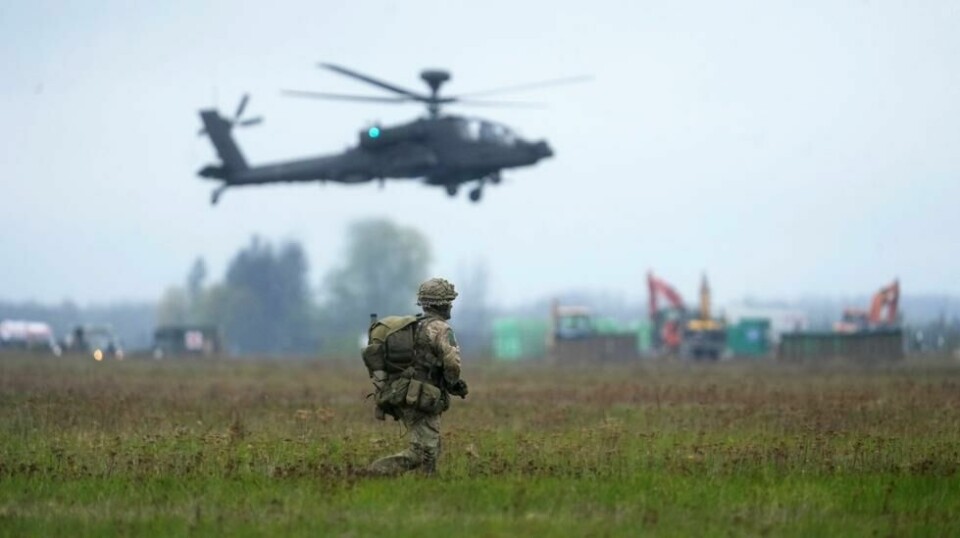 En fallskjermsoldat og en Boeing AH-64 Apache helikopter fra øvelsen Swift Response nær Nurmsi. Foto: REUTERS/Ints Kalnins